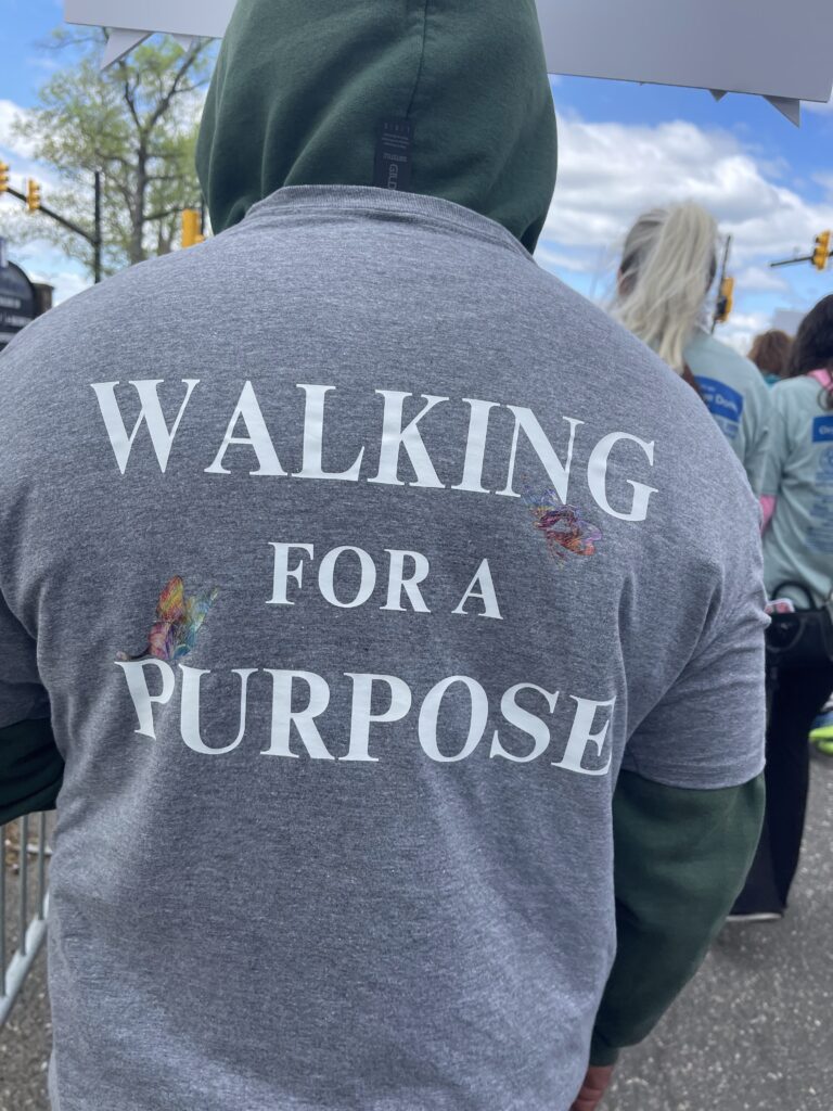 Mission For Life Inc at the 2025 Donor Dash Walk. A man with photo taken from the back in a grey short with words Walking for a purpose