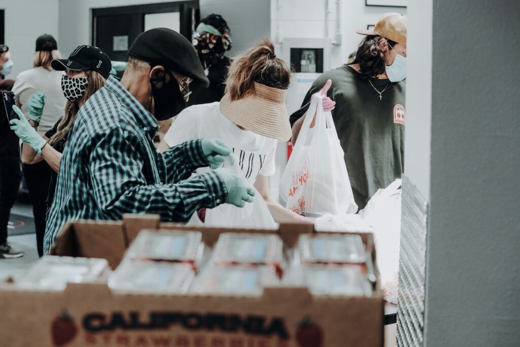 volunteers with mask and gloves on putting donation items  in bags to give a way. 
Photo by Joel Muniz on Unsplash   